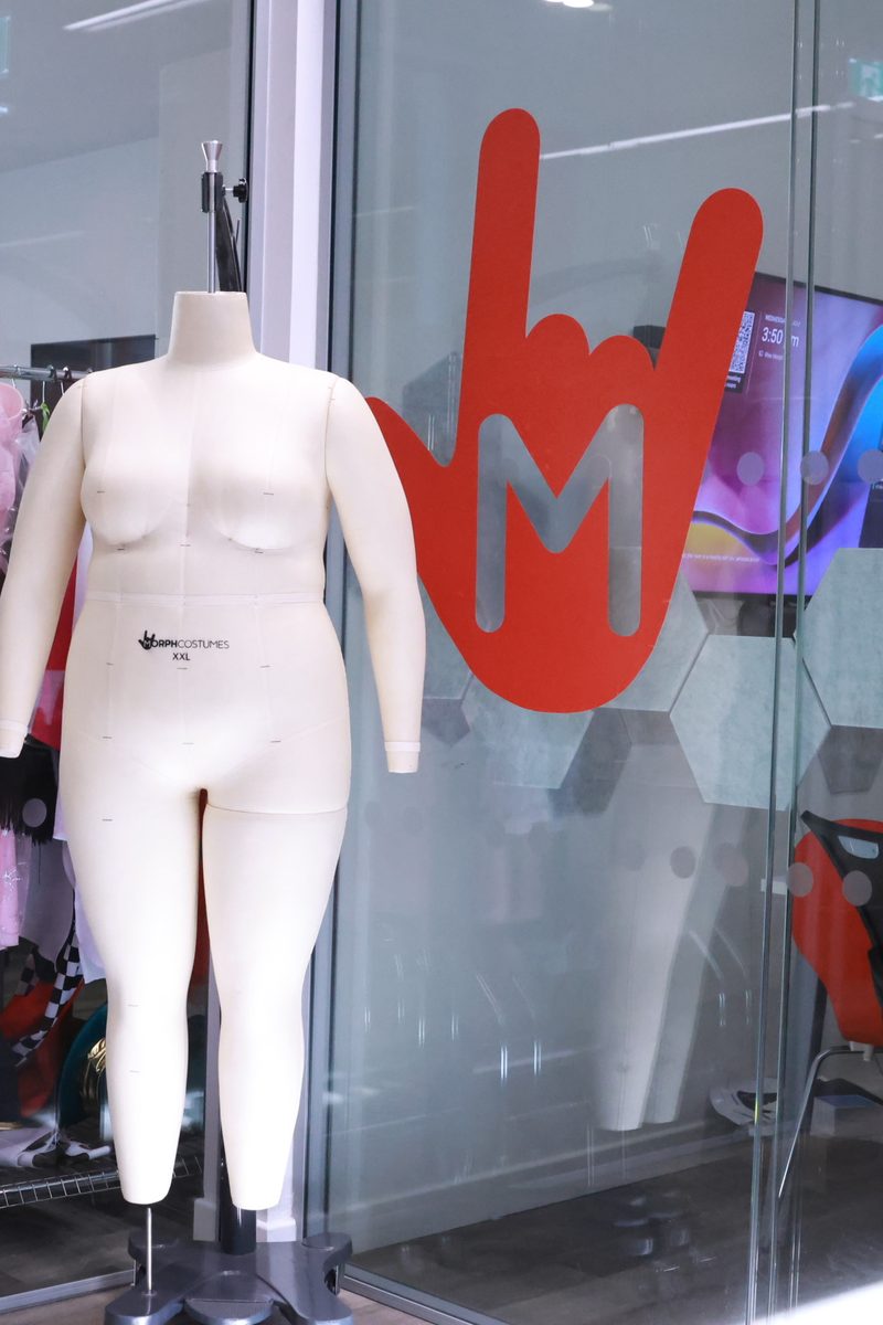 A tailor's mannequin and the red Morph hand logo in the glass wall of the MorphCostumes office in Edinburgh